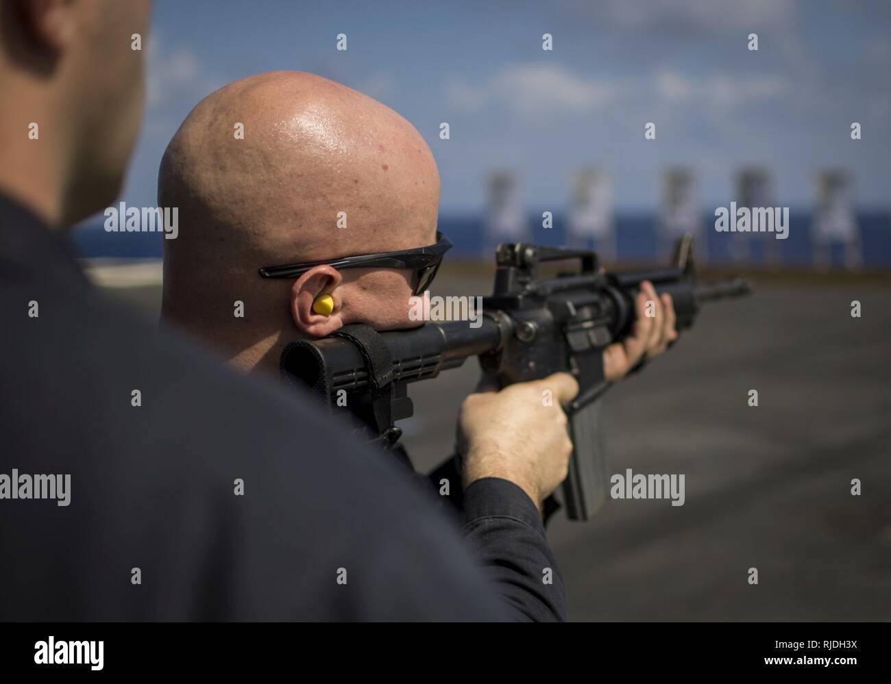 PACIFIC OCEAN (Jan. 21, 2018) Master-at-Arms 1st Class Cody Schilcher fires an M4A1 carbine during a small-arms qualification course on the flight deck of Nimitz-class aircraft carrier USS Carl Vinson (CVN 70). Carl Vinson Strike Group is currently operating in the Pacific as part of a regularly scheduled deployment. Stock Photo