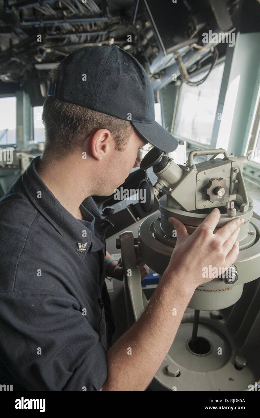 PACIFIC OCEAN (Jan. 21, 2018) Boatswain’s Mate 3rd Class Daniel Lynch, a Detroit native, reads the ship’s bearing using a telescopic alidade on the bridge aboard the amphibious assault ship USS America (LHA 6) America, part of the America Amphibious Ready Group, with embarked 15th Marine Expeditionary Unit, is returning from a 7-month deployment to the U.S. 3rd, 5th and 7th fleet areas of operations. Stock Photo