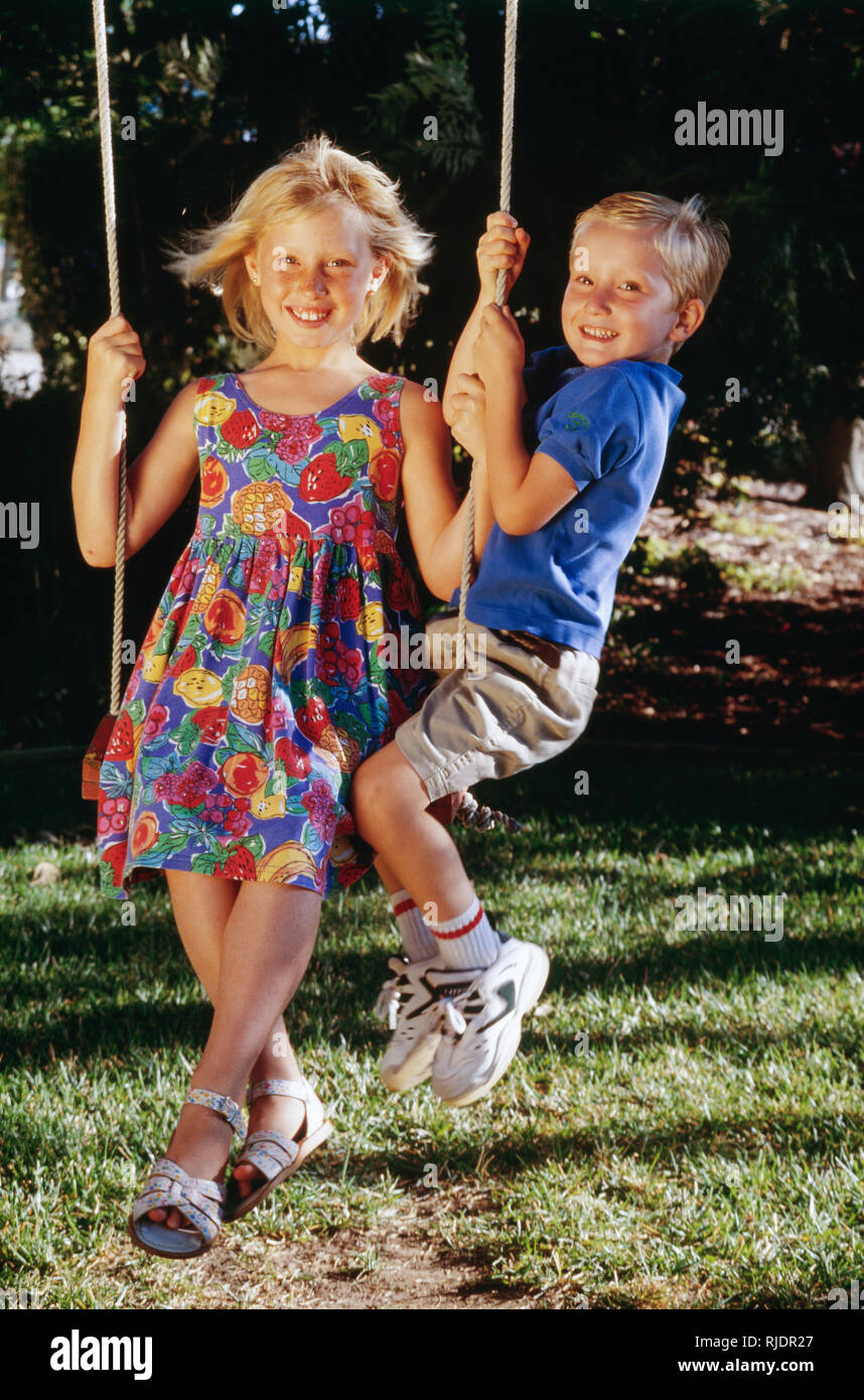 Cute Blond Siblings Play on a Swing Together, USA Stock Photo