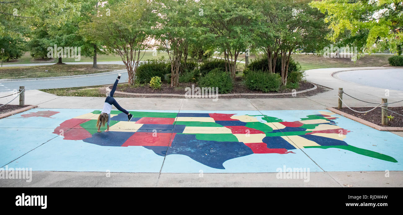 A young girl doing a cartwheel on a large sidewalk mural of the USA. Stock Photo