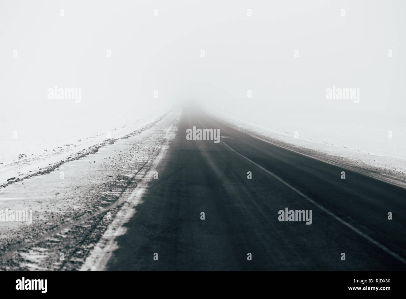 Asphalt road going through a snowy field Stock Photo - Alamy