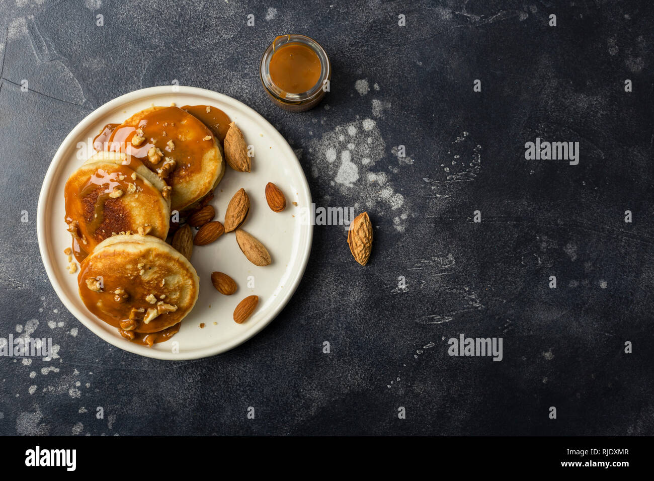Free space with american pancakes with caramel and nuts at black background. Left edge composition. Top view concept of healthy breakfast Stock Photo