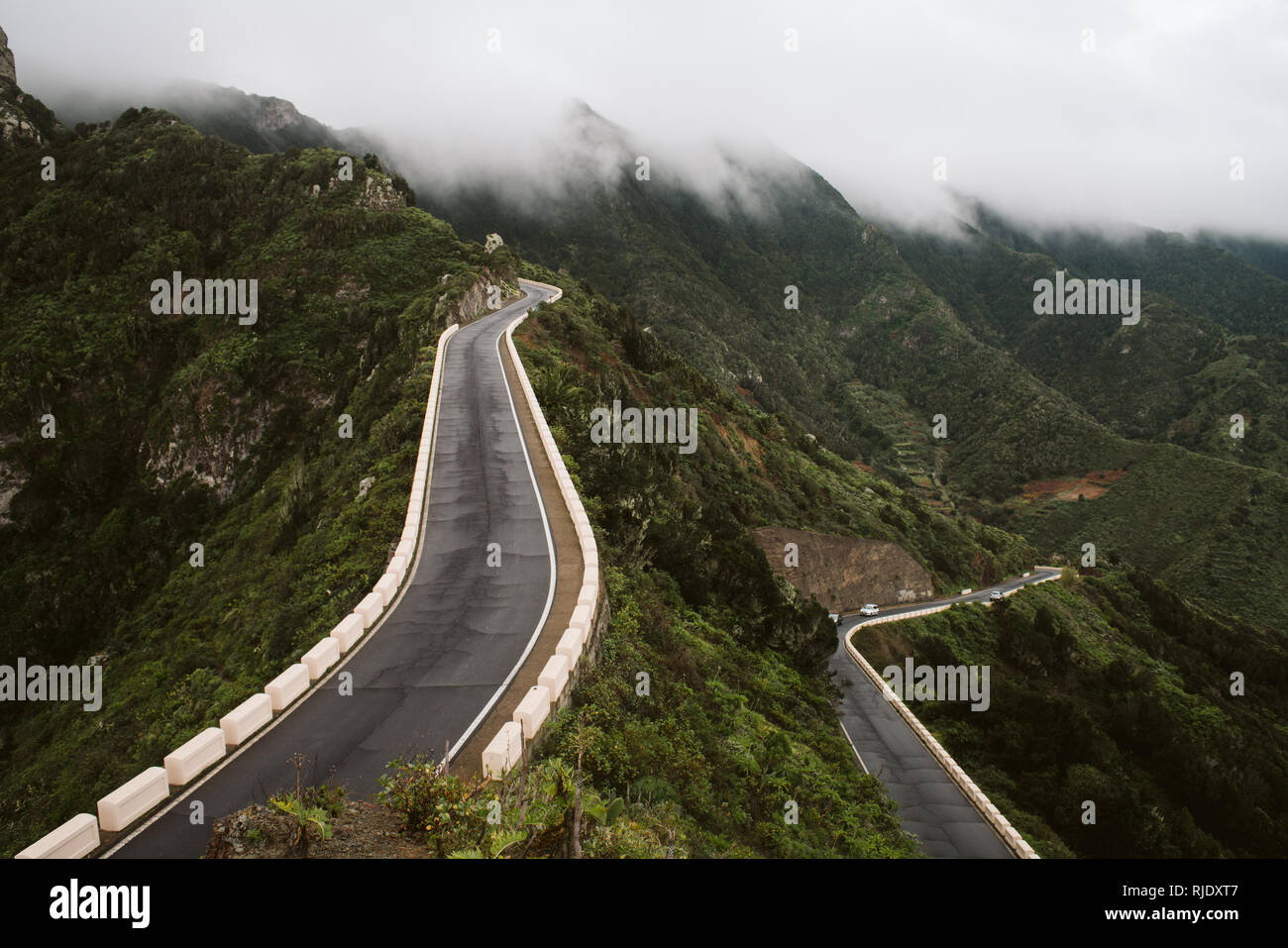 Two asphalt roads going through mountain ridge on wonderful misty day ...
