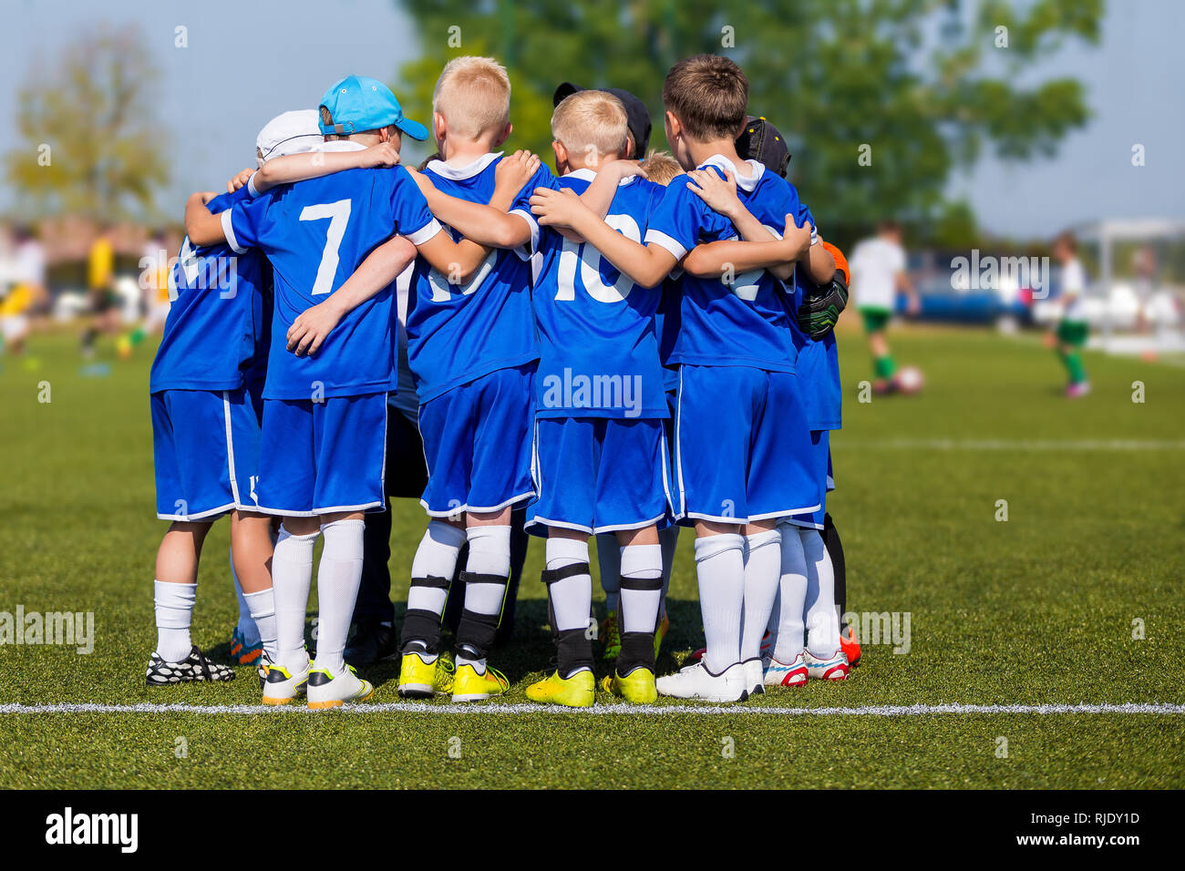 Kids Sport Team Gathering. Children Play Sports. Boys in Sports Jersey Uniforms Having Shout Team. Coach Giving Young Soccer Team Instructions. Youth  Stock Photo