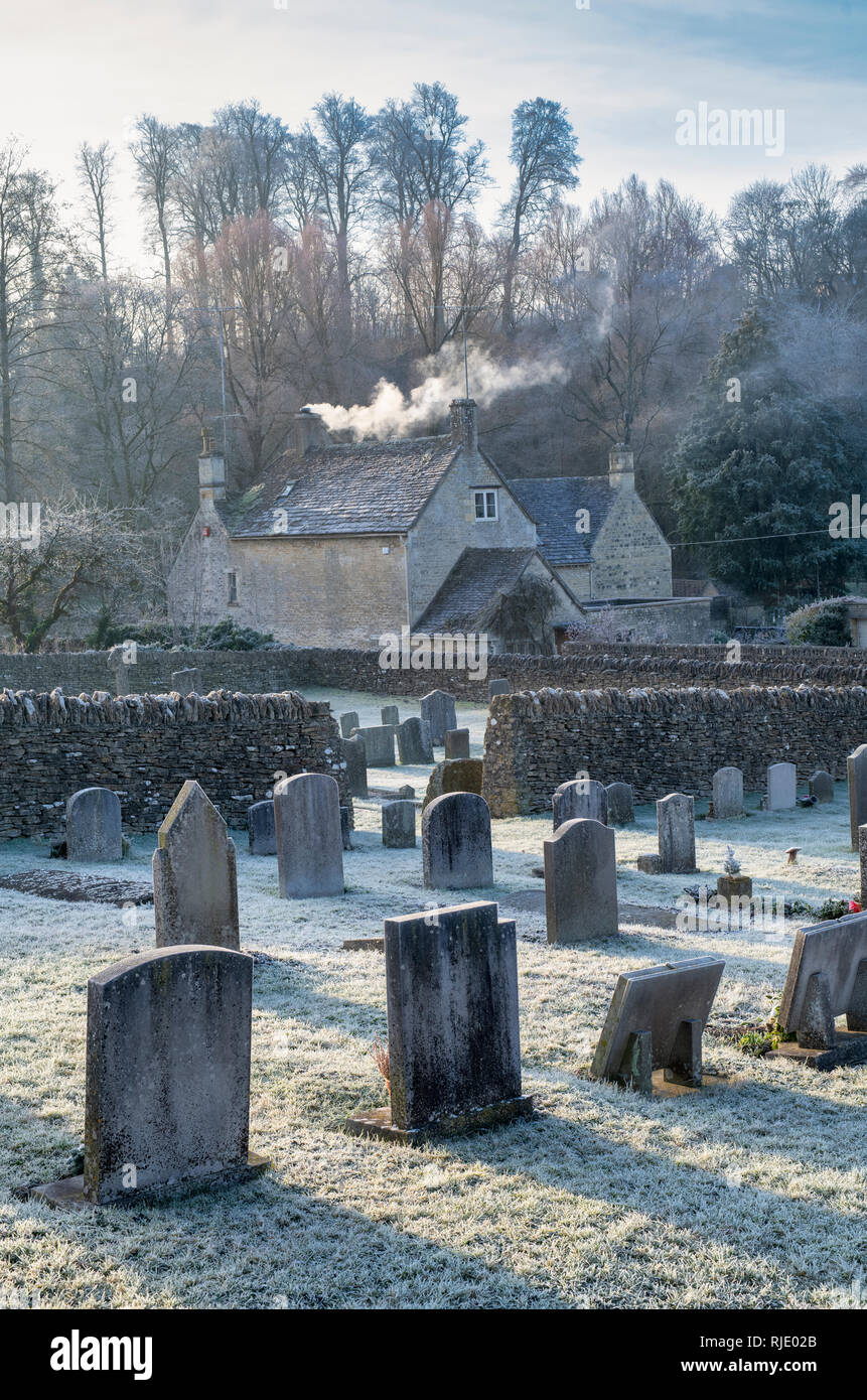 St. Mary's Church cemetery and cottages in the winter frost. Bibury, Cotswolds, Gloucestershire, England Stock Photo