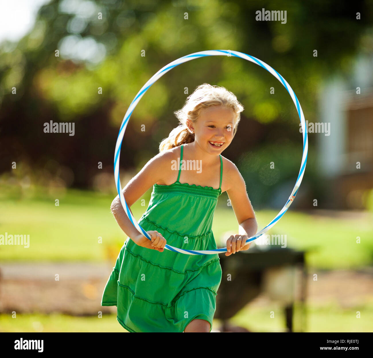 Happy young girl playing with a hula hoop in her back yard. Stock Photo