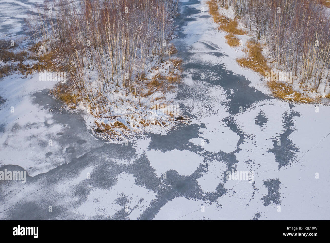 Aerial view of the winter snow covered forest and frozen lake from ...