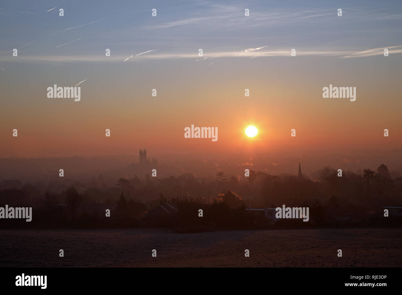 Sunrise over Canterbury on a cold, crisp January morning with aircraft vapour trails in the sky. Stock Photo