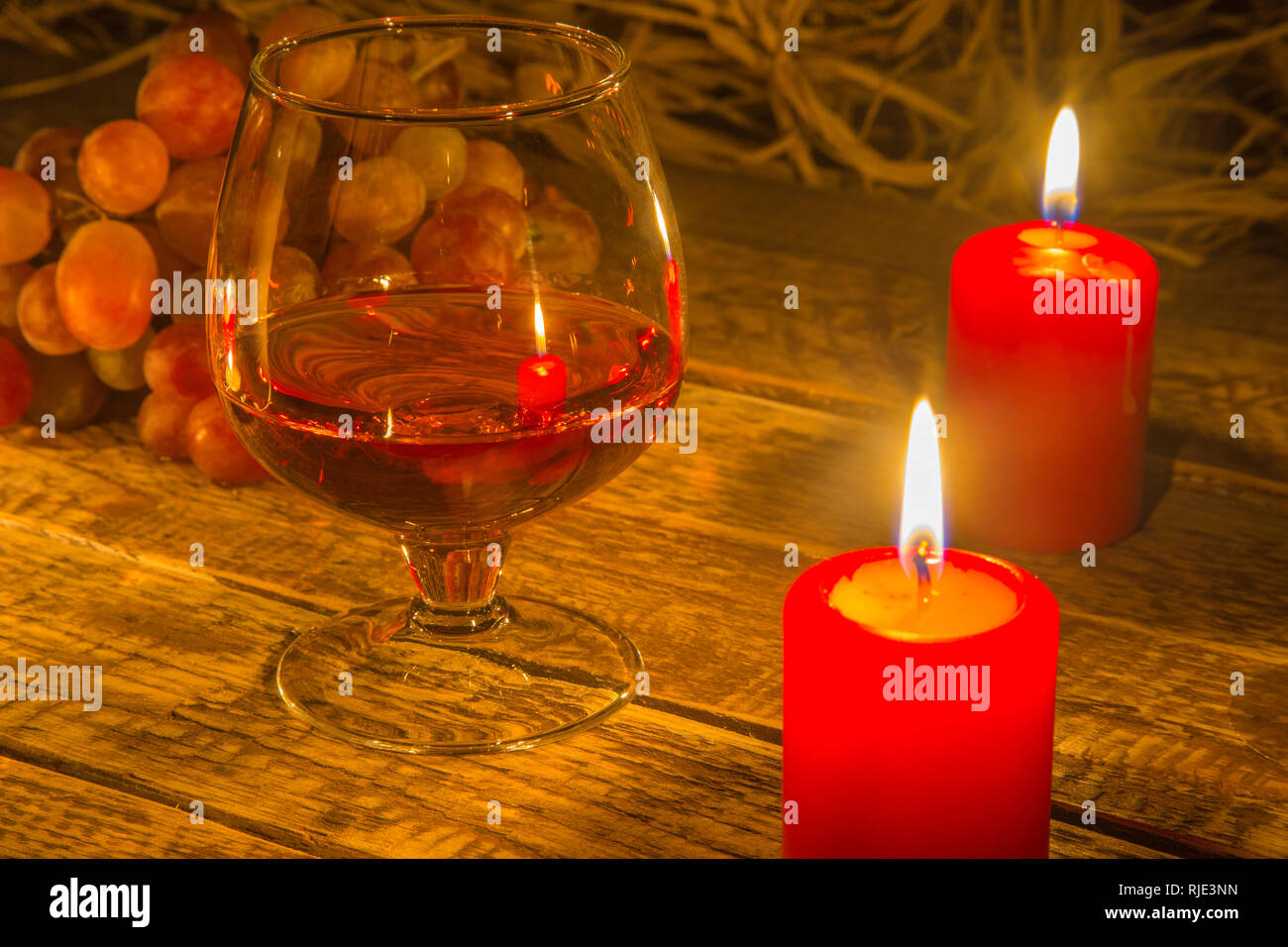 Glass with Cognac or Brandy, fresh grapes and candles. still life in