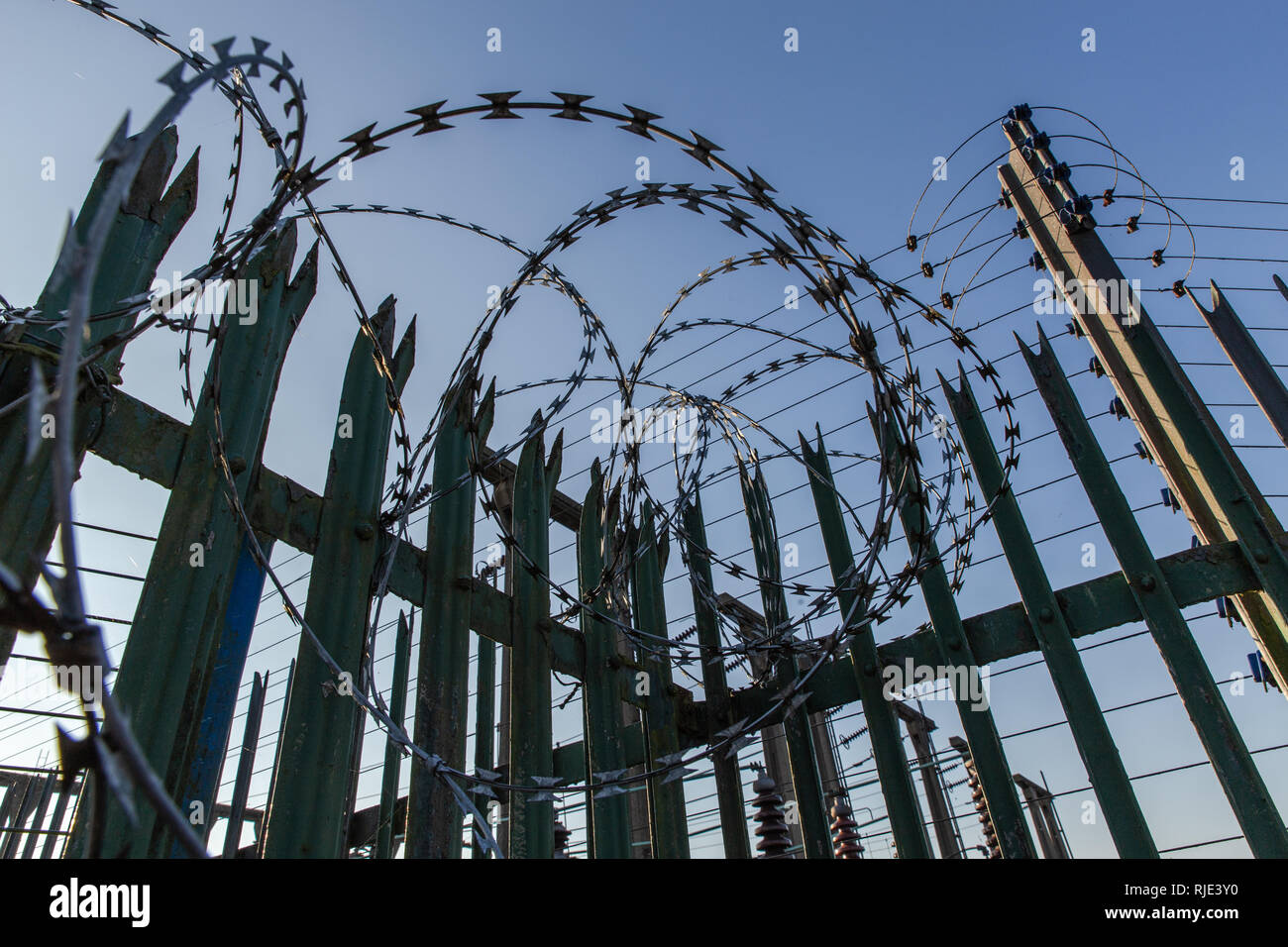 Concertina razor wire used on top of a spiked metal fence to provide security and deter unauthorised access to a  power distribution sub station. Stock Photo