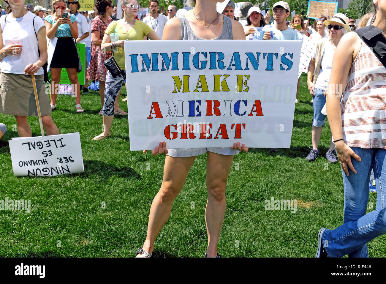 A woman holds an Immigrants Make America Great sign at a rally against Trump immigration policies in downtown Cleveland, Ohio, USA on June 30, 2018. Stock Photo