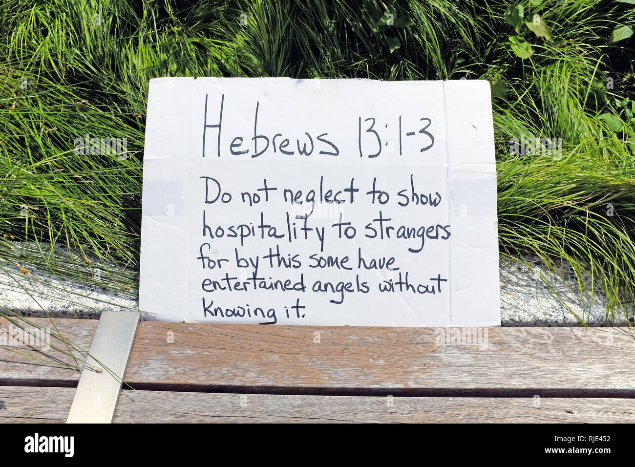 A placard on which is written Hebrews 13:1-3 about showing hospitality to strangers is on display at a pro-immigrant rally in Cleveland, Ohio, USA. Stock Photo