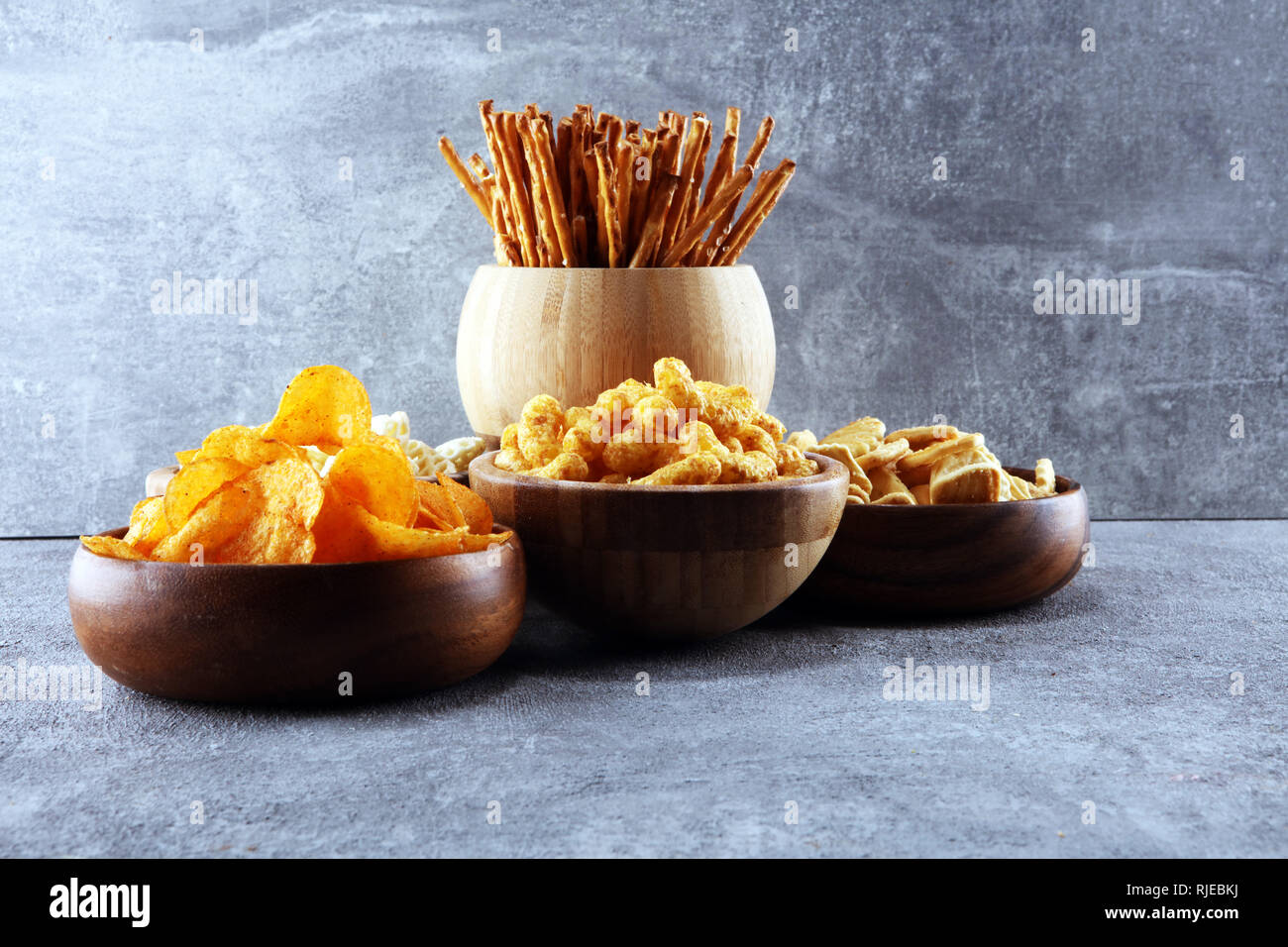 Salty snacks. Pretzels, chips, crackers in wooden bowls. Unhealthy