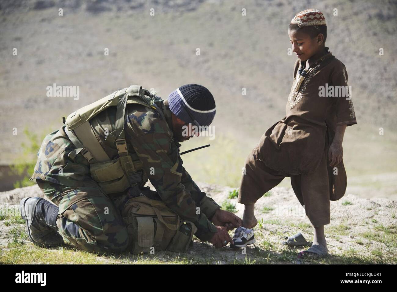 An Afghan National Army special forces soldier helps a boy try on a new  pair of shoes in Tagaw district, Uruzgan province, Afghanistan, April 14.  The soldier gave the boy the shoes