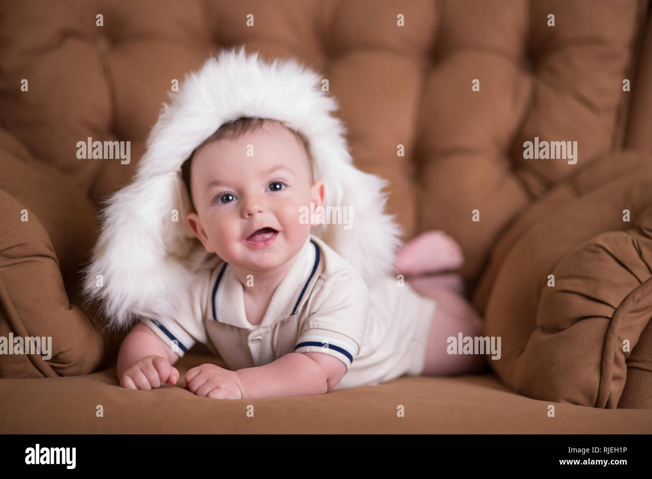 Happy newborn child baby boy with pink cheeks posing on hege retro