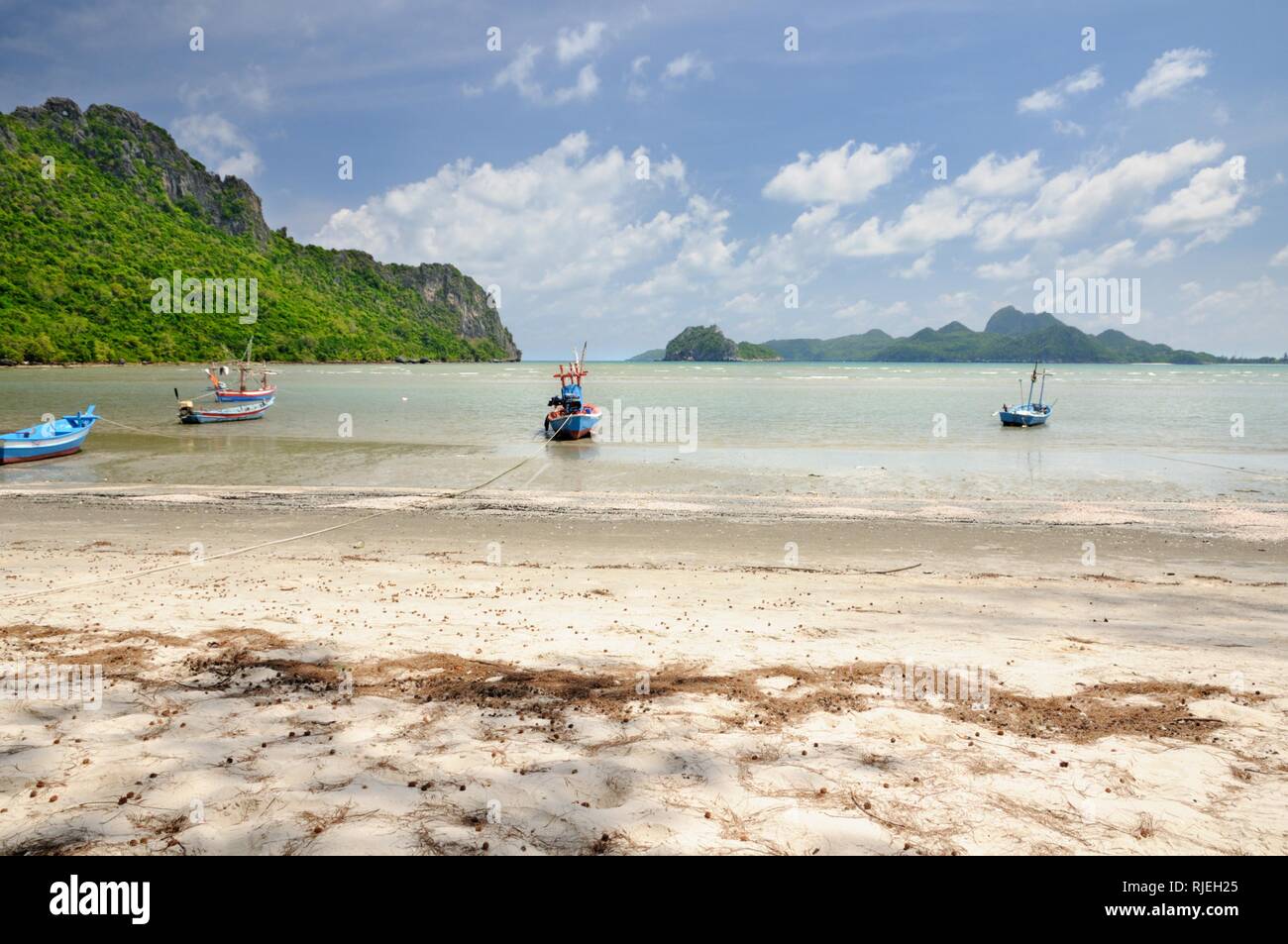 Thai longtail fishing boats on sandy beach in Ao Manao bay during low tide in Prachuap Khiri Khan province of Thailand Stock Photo