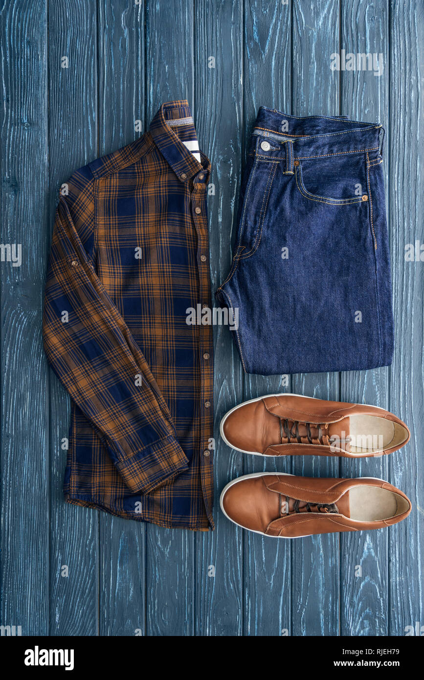 Top view of checkered shirt, jeans and brown shoes on wooden background  Stock Photo - Alamy