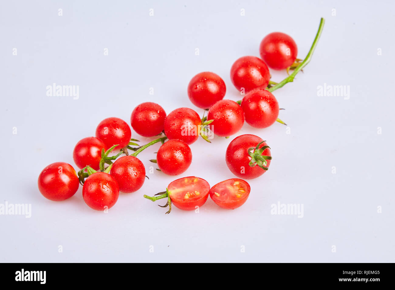 Branches of red organic fresh cherry tomatoes on a white background ...