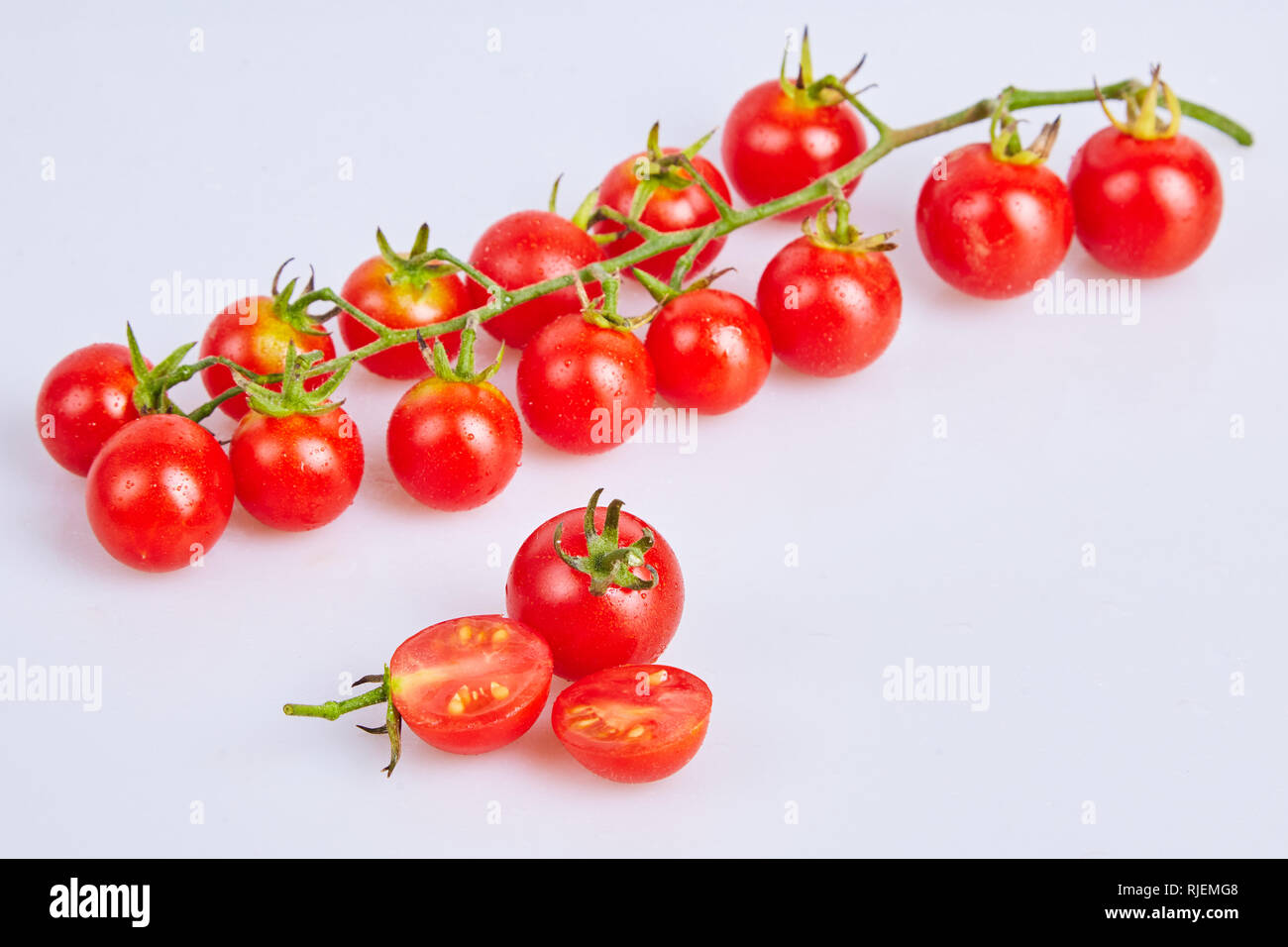 Branches of red organic fresh cherry tomatoes on a white background ...