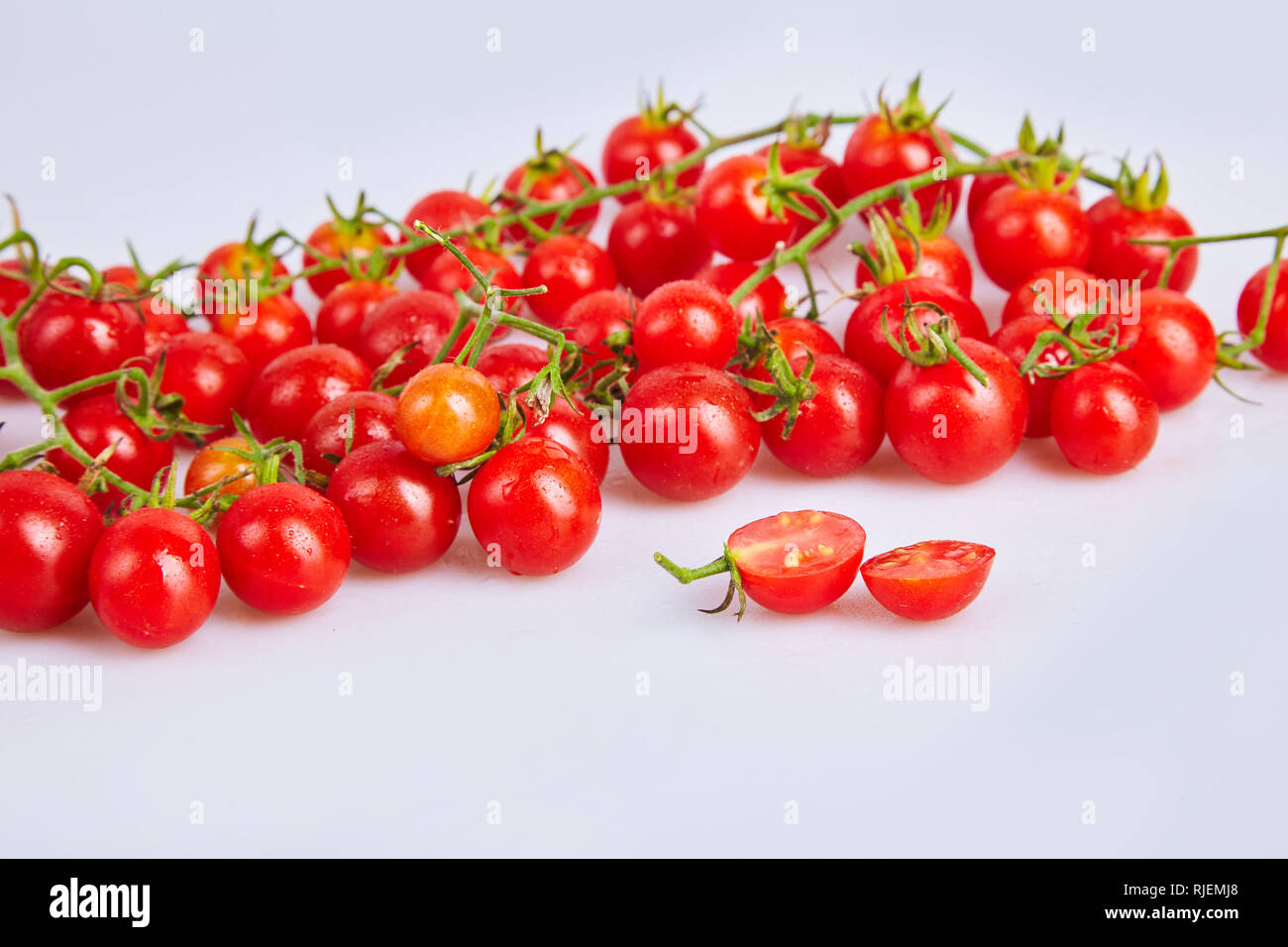 Branches of red organic fresh cherry tomatoes on a white background ...