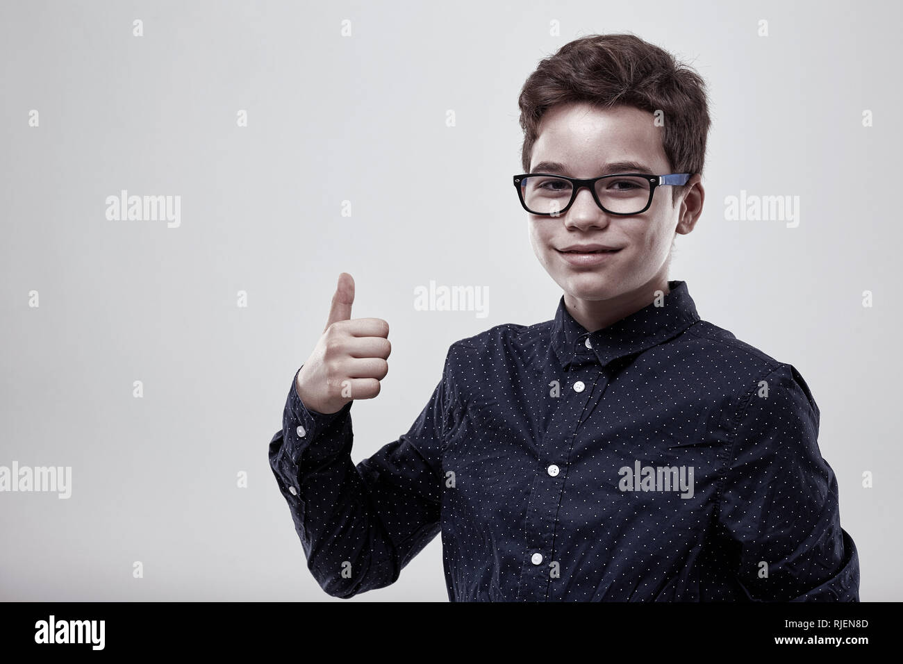 Schoolboy showing thumbs up sign on gray background Stock Photo - Alamy