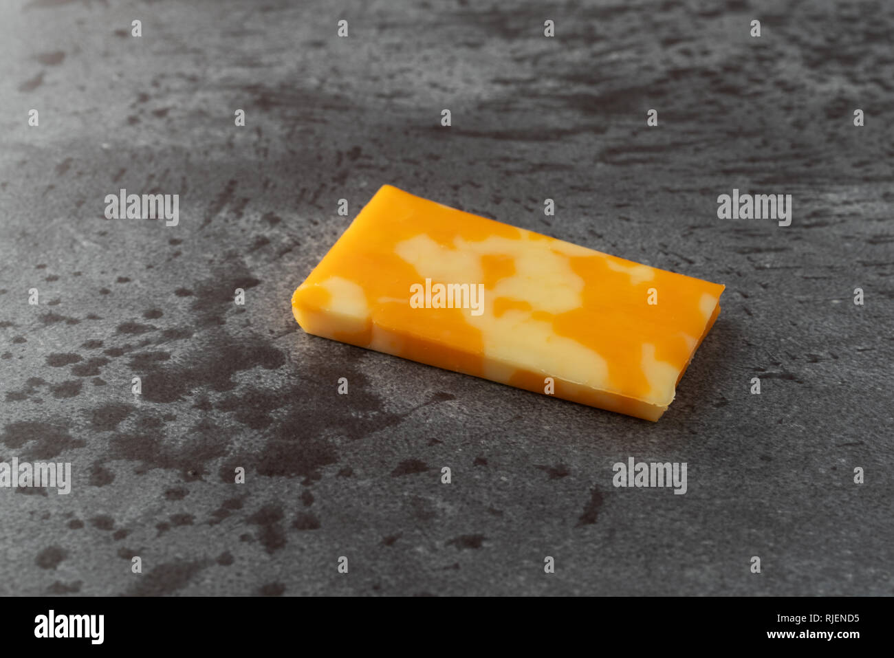 Side view of a single Colby Jack cheese bar on a gray background Stock