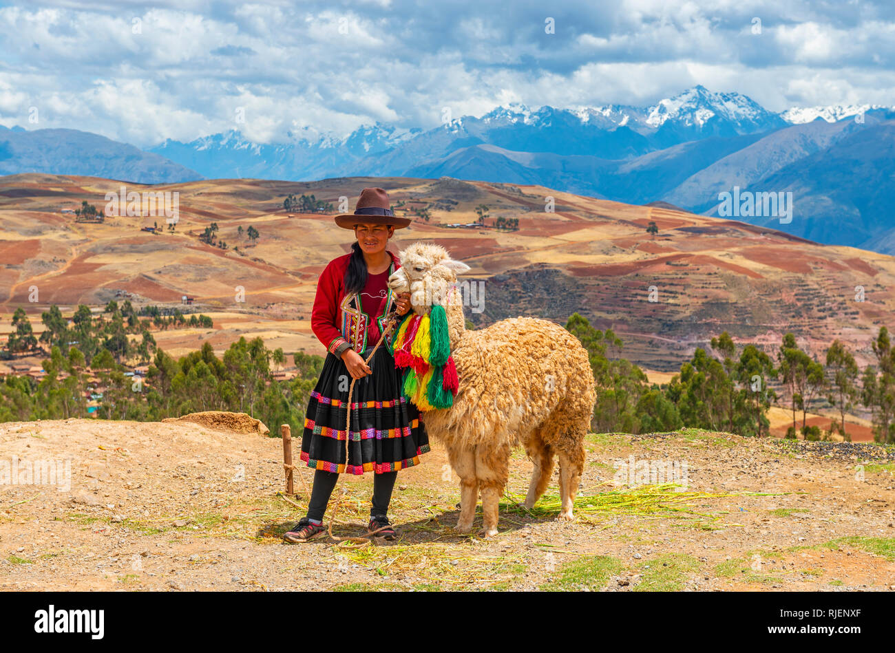 Indigenous Peruvian Quechua lady in traditional clothing with her alpaca in the Sacred Valley of the Inca and the Andes mountain range, Cusco, Peru. Stock Photo