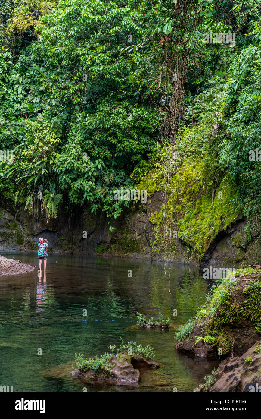A nice photo of a mother with her child admiring the beautiful tropical jungle landscape surrounding a shallow river at Drake Bay, Costa Rica Stock Photo
