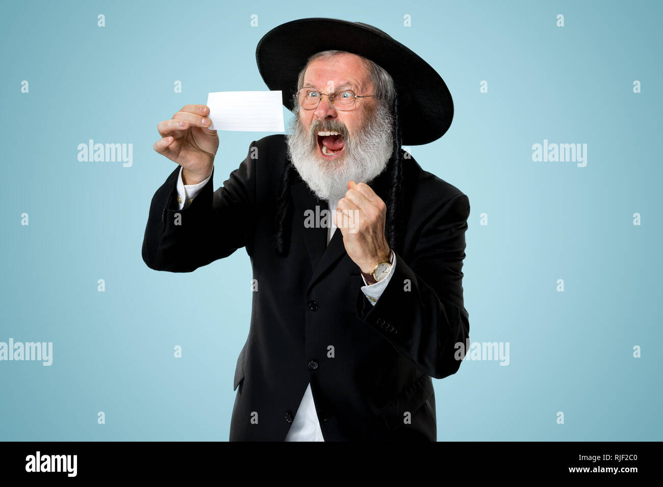 Portrait of a senior orthodox Hasdim Jewish man with bet slip at studio. The holiday, celebration, judaism, bet, betting concept. Stock Photo