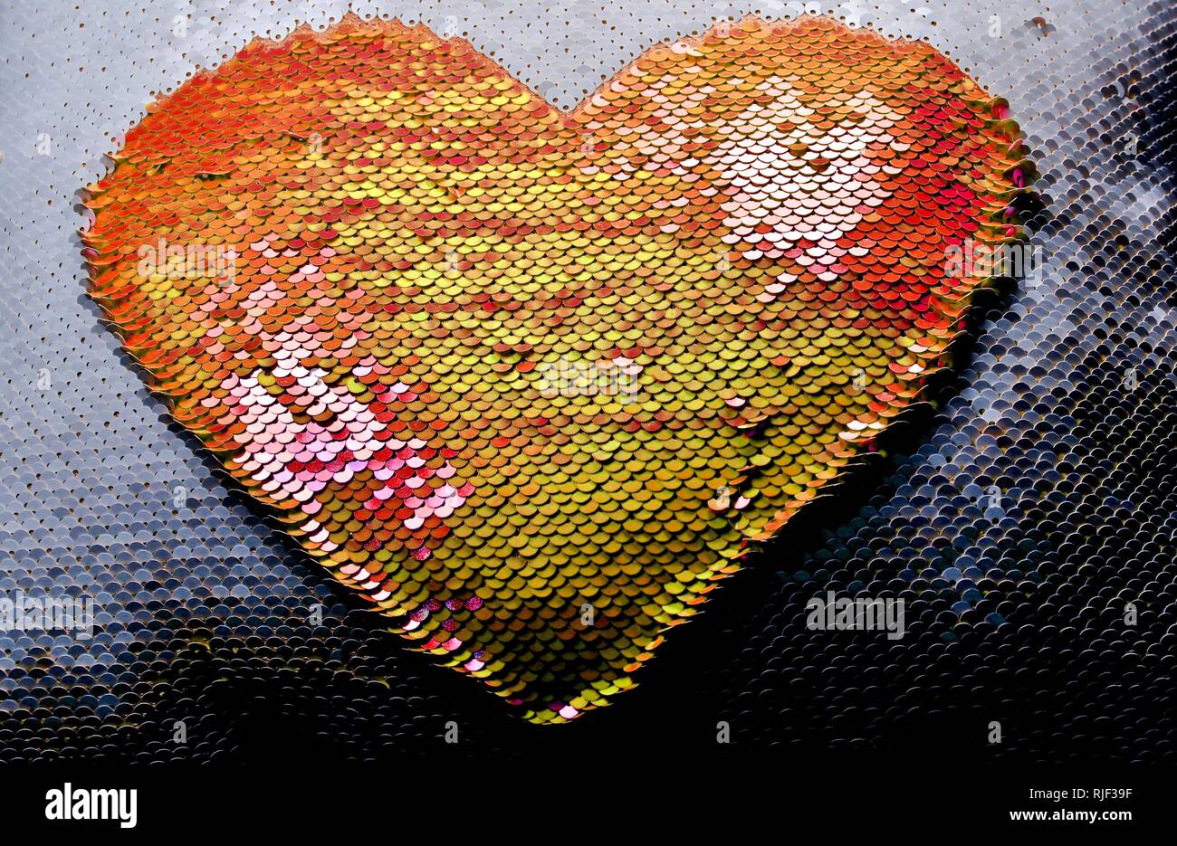Coral and Yellow colored sequins in the shape of a heart. Stock Photo