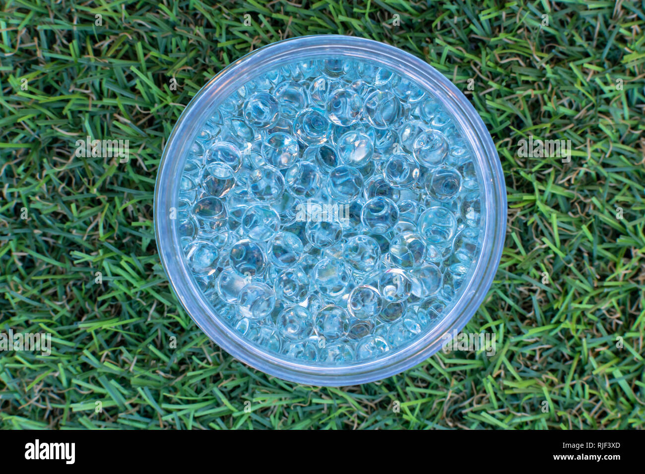 Blue gel balls in the middle on green artificial grass background Stock