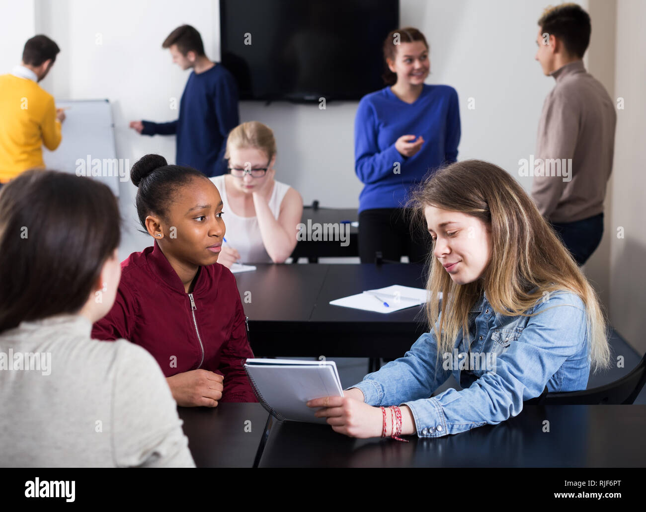 Positive girl consulting fellow student during test examination in