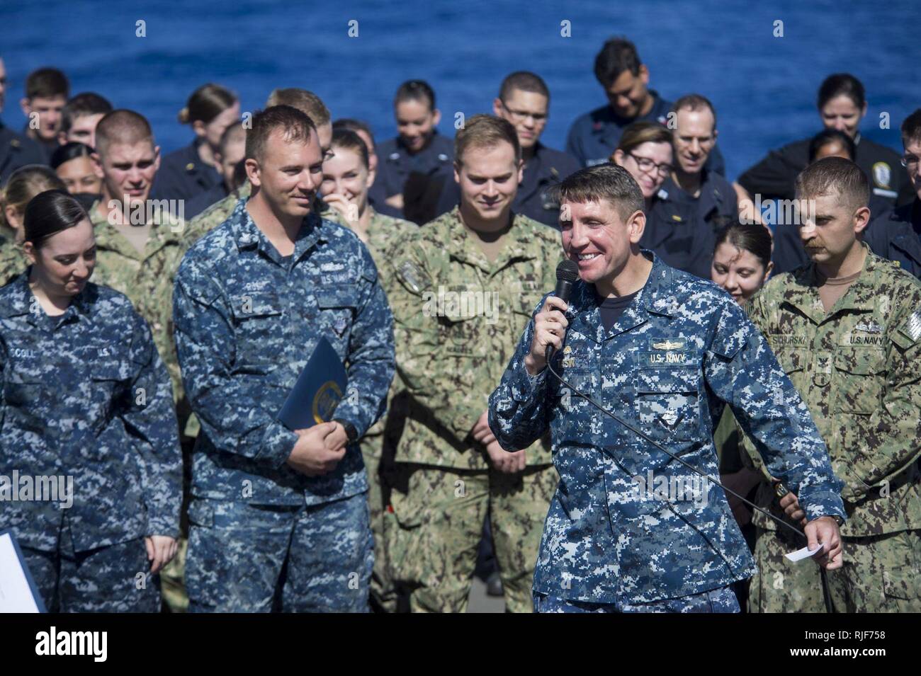 PACIFIC OCEAN (Feb. 12, 2015) – Cmdr. Scott T. Tasin, commanding officer of the dock landing ship USS Comstock (LSD 45), addresses Sailors during an all-hands call on the flight deck. Comstock, part of the Makin Island Amphibious Ready Group, and the embarked 11th Marine Expeditionary Unit are returning to homeport San Diego following a seven-month deployment to the Western Pacific and the U.S. Central Command areas of operation. Stock Photo