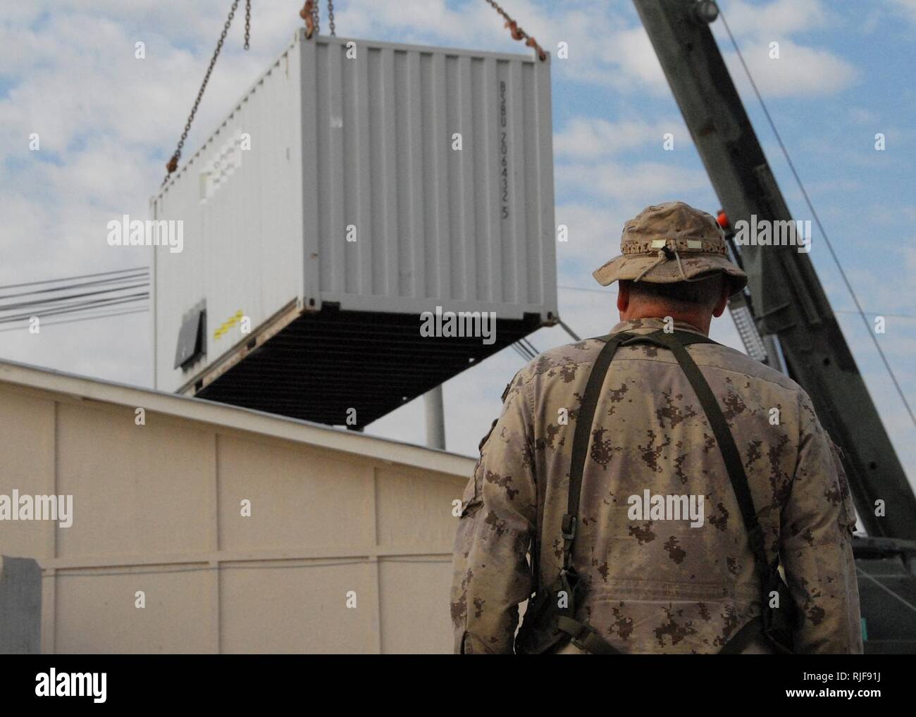 KANDAHAR, Afghanistan--A Canadian soldier with the International Security Assistance Force Regional Command South Engineers oversees a crane operation as it sets down a power supply container that was occupying the space where a new medical operation facility will be put in place at the ROLE 3 Hospital near Kandahar Air Field on February 3, 2008. The one-day project is a joint venture with the Task Forces operating in the ISAF RC South area of operation. The new operation room is expected to be fully operational later in the week. ISAF Stock Photo