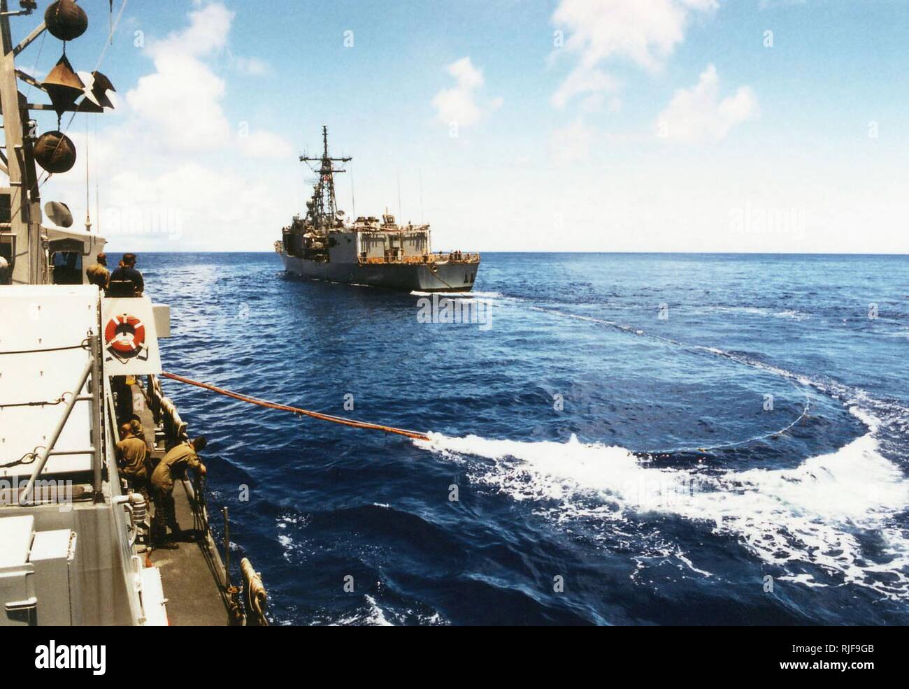 A view taken from onboard the US Navy (USN) Cyclone Class Coastal Defense Ship, USS HURRICANE (PC 3), showing as a trailing refueling line being extended from the USN Oliver Hazard Perry Class: Guided Missile Frigate, USS JOHN H. SIDES (FFG 14), as the two ships conduct Replenishment At Sea (RAS) operations while underway in the Pacific Ocean participating in a Coordination Afloat Readiness and Training (CARAT) Exercise, while executing the first trans-Pacific cruise of a Patrol Forces boat. Stock Photo