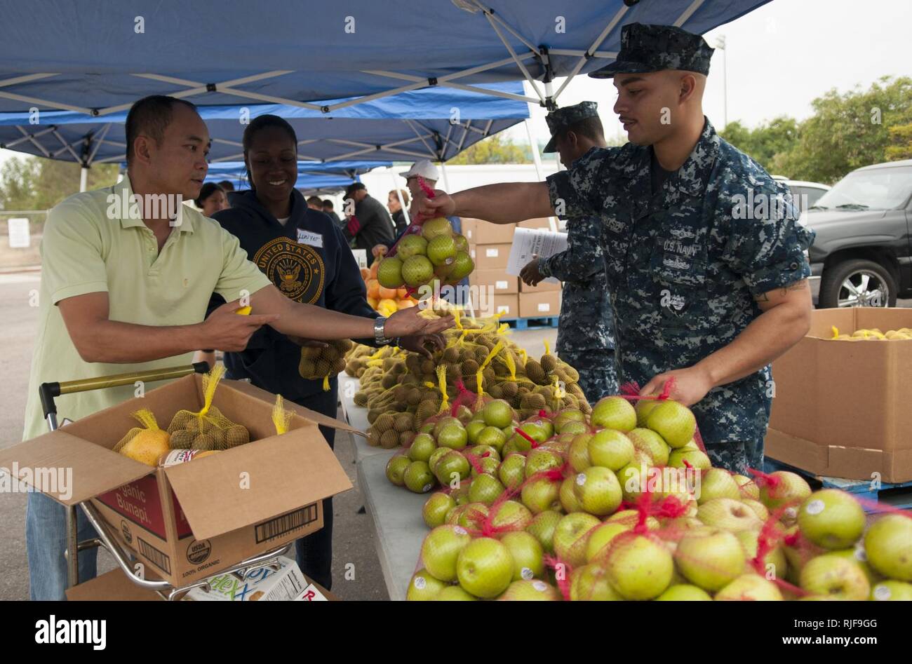 Intelligence Specialist 3rd Class Jermaine Crosby, assigned to Commander, U.S. 3rd Fleet, distributes produce to families during the Neighborhood Exchange Food Bank Distribution event at the Murphy Canyon Armed Services YMCA (ASYMCA) Headquarters in San Diego. Sailors volunteered with the ASYMCA, who partnered with the San Diego Food Bank, to provide qualifying families with fresh produce and non-perishable items such as bottled juices, cereal and canned stews. Stock Photo