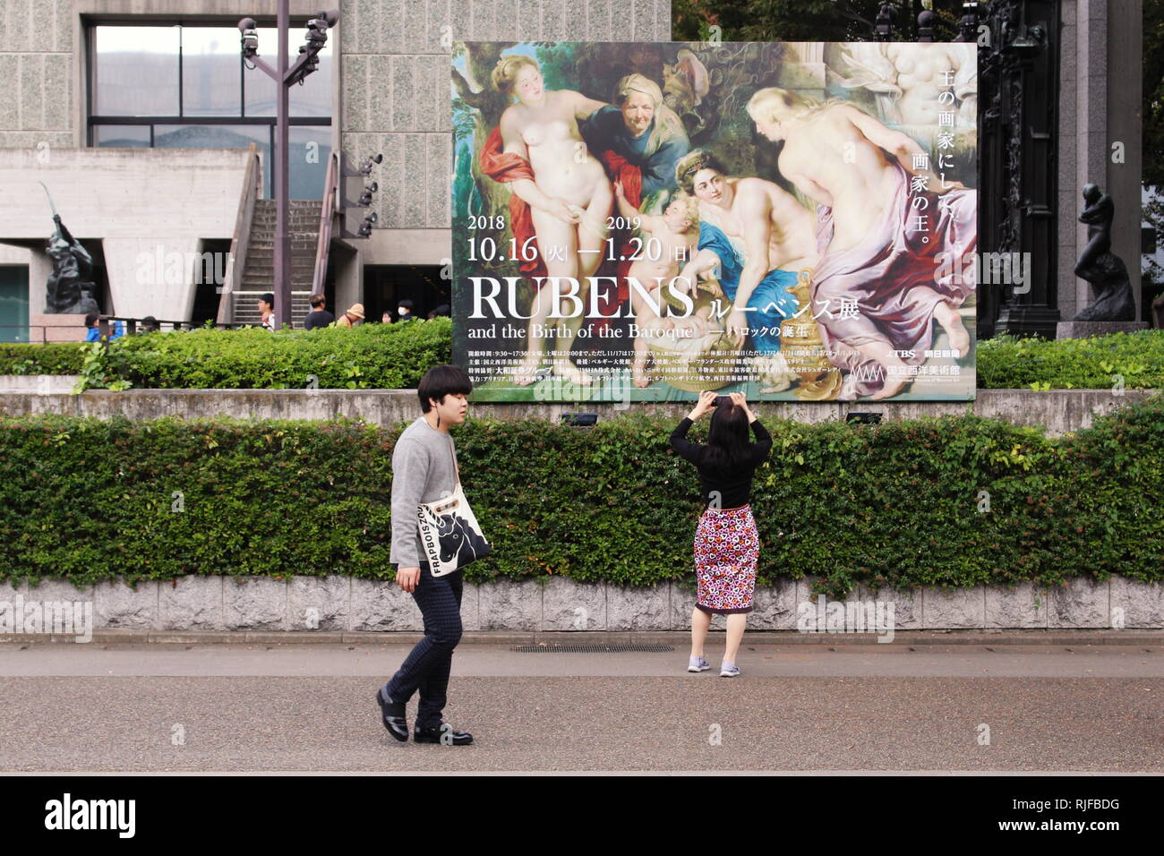 A visitor takes a photo of a large billboard advertising a Rubens exhibition in front of the National Museum of Western Art. Stock Photo