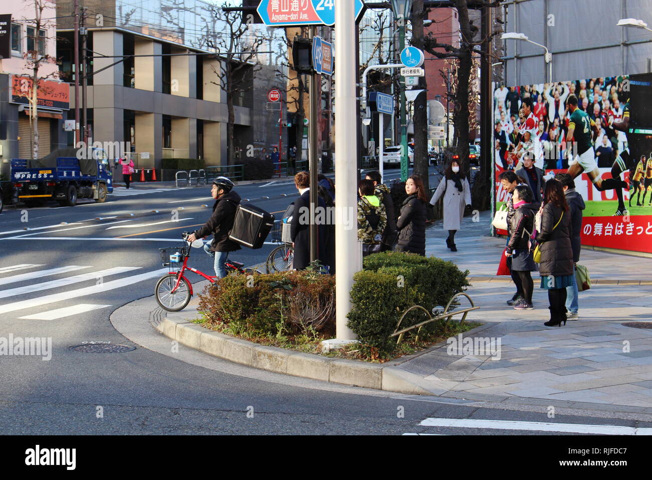 People to cross the street on a sidewalk in Aoyama where there is a billboard advertsing the 2019 Rugby World Cup. (January 2019) Stock Photo