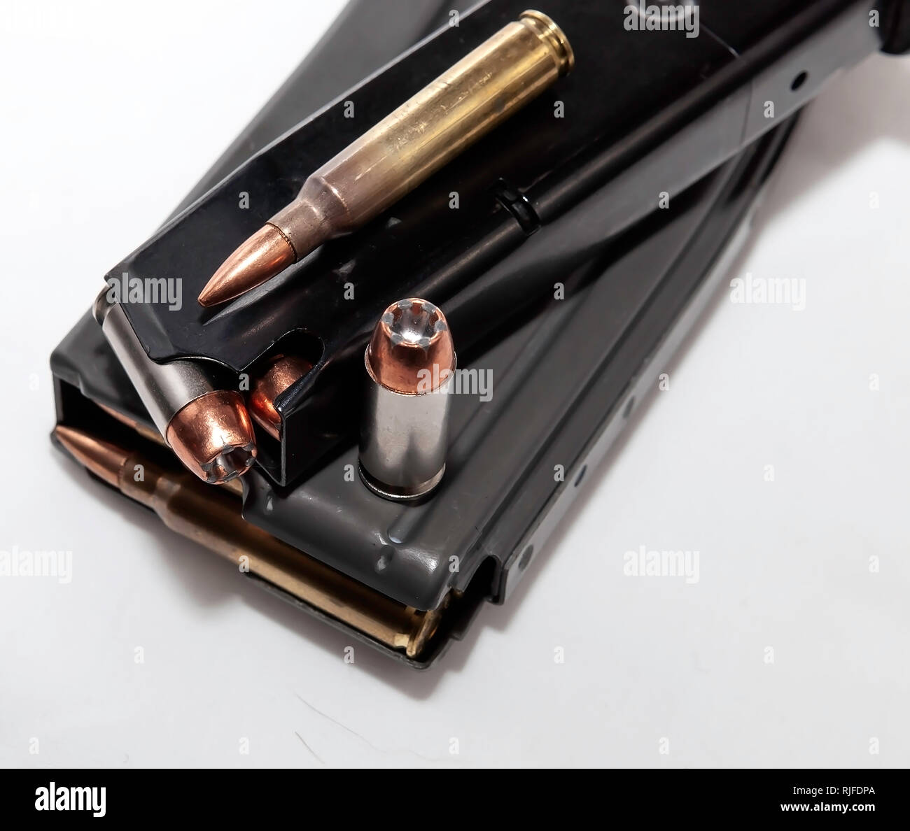Two magazines, one for a pistol and one for a rifle both loaded with bullets with a 40 caliber and 223 caliber shown on top of them on a white backgro Stock Photo
