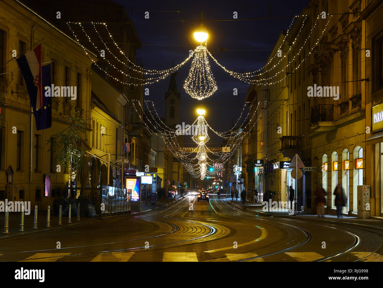 Streets of Zagreb with twisting tram tracks, illuminated with hanging christmas light, long exposure to blur movement. Stock Photo