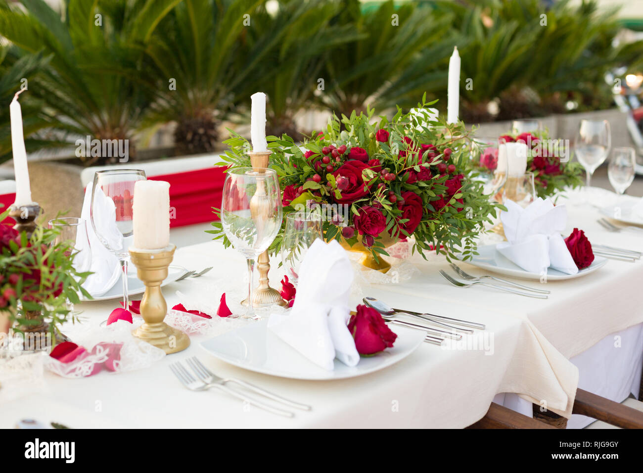table for a wedding dinner decorated with red flowers and greenery Stock Photo