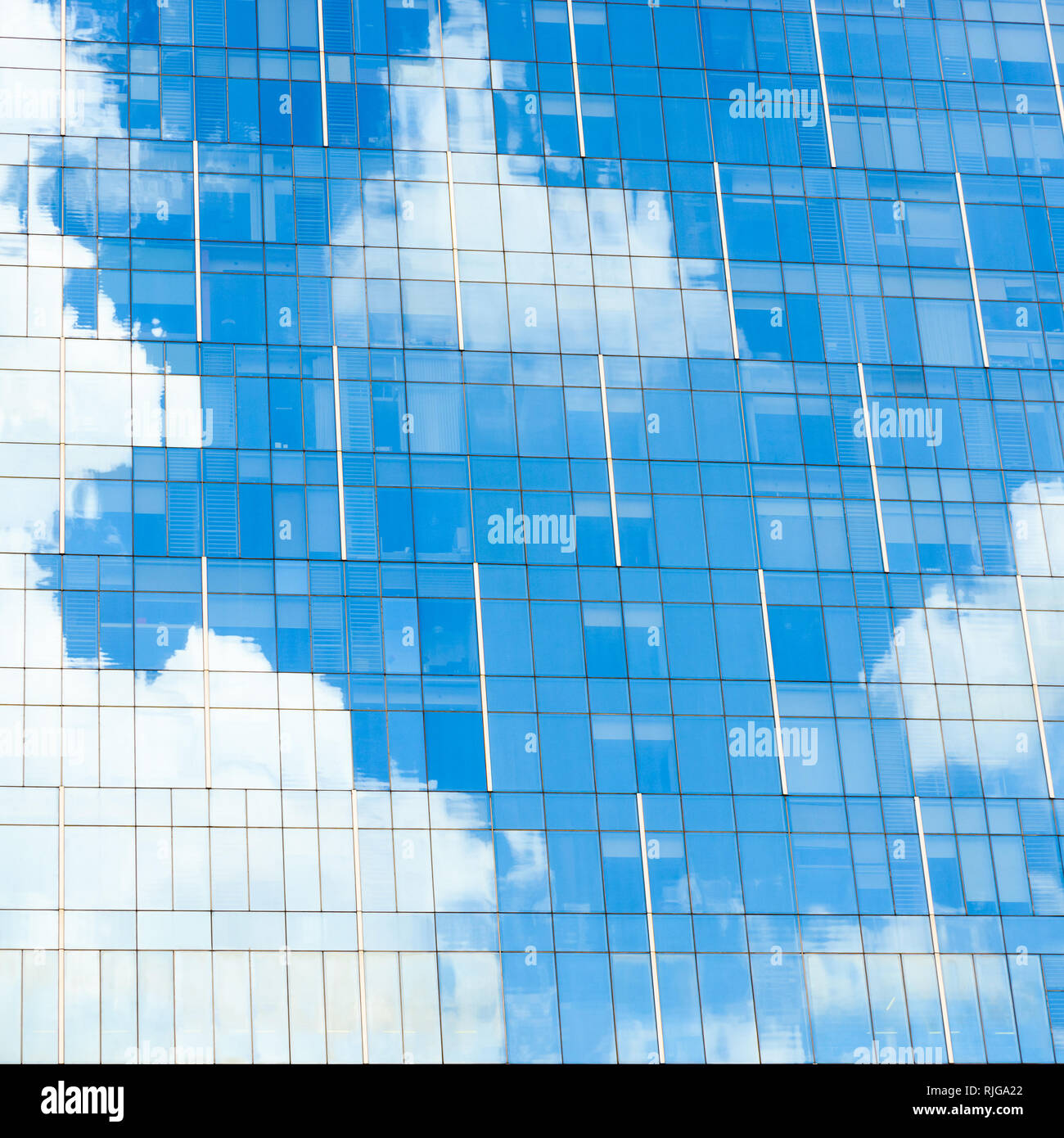 Blue sky and white clouds reflection on glass facade of a modern office building Stock Photo