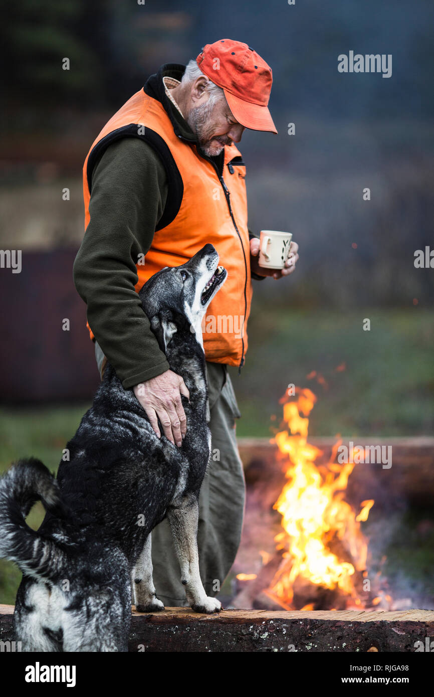 Man with dog at campfire Stock Photo