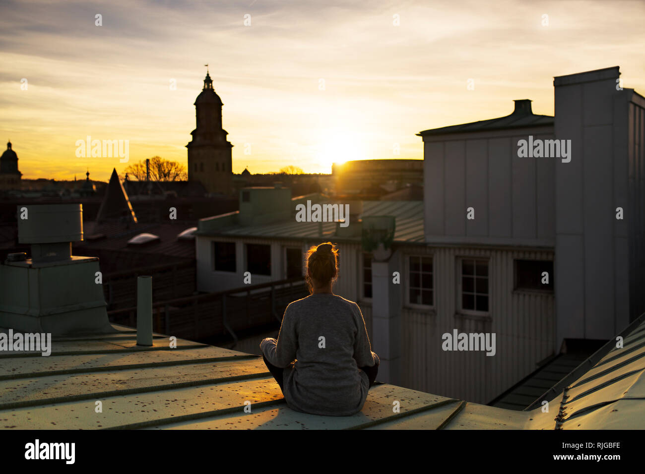 Woman on roof looking at sunset Stock Photo