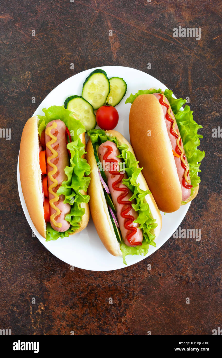 Tasty hot dogs with sausage grill, ketchup, mustard, lettuce, tomatoes