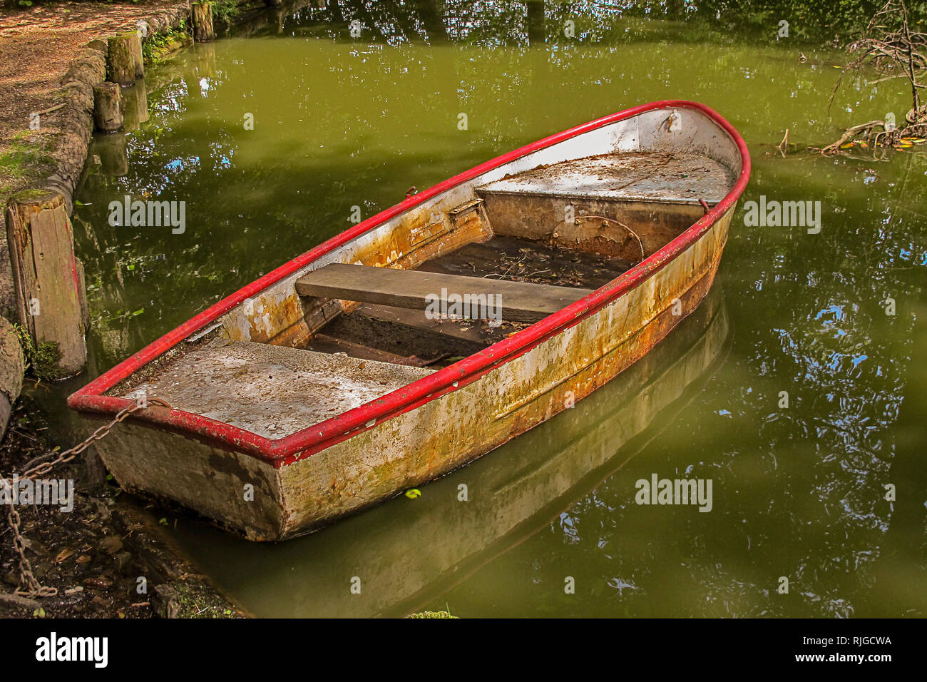 old dirty rowing boat on a small pond Stock Photo - Alamy