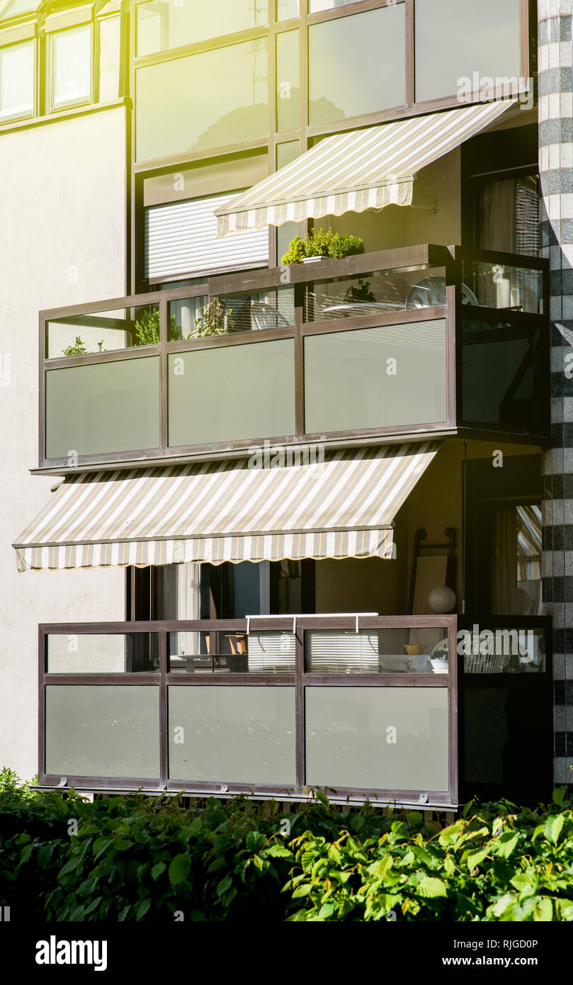 Apartment building with balcony with awning opened covered by sunshield on a warm summer day