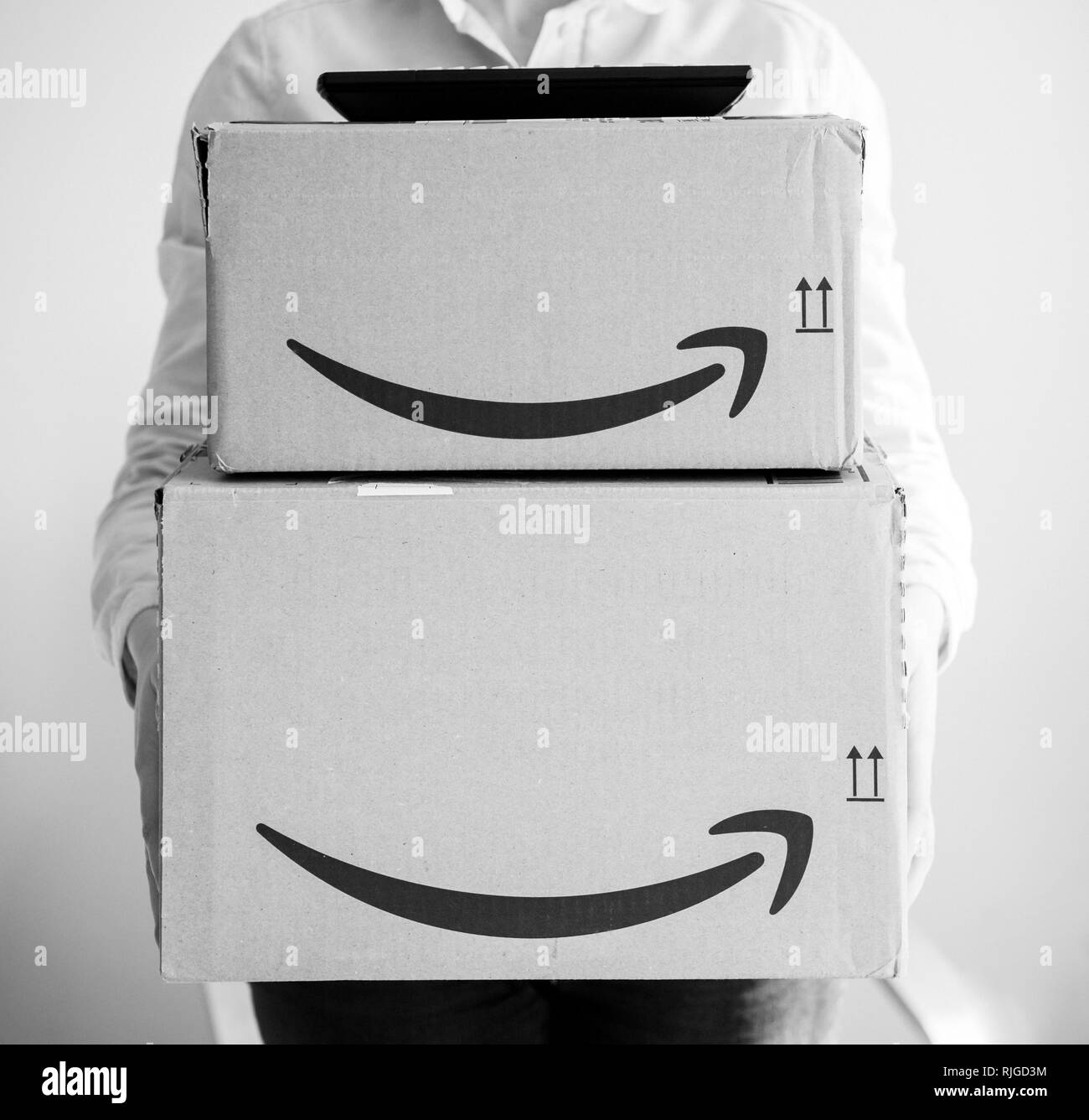 PARIS, FRANCE - MAR 16, 2018: Happy smiling woman holding two large Amazon Prime cardboard boxing after delivery black and white - tv set on toop of boxes  Stock Photo