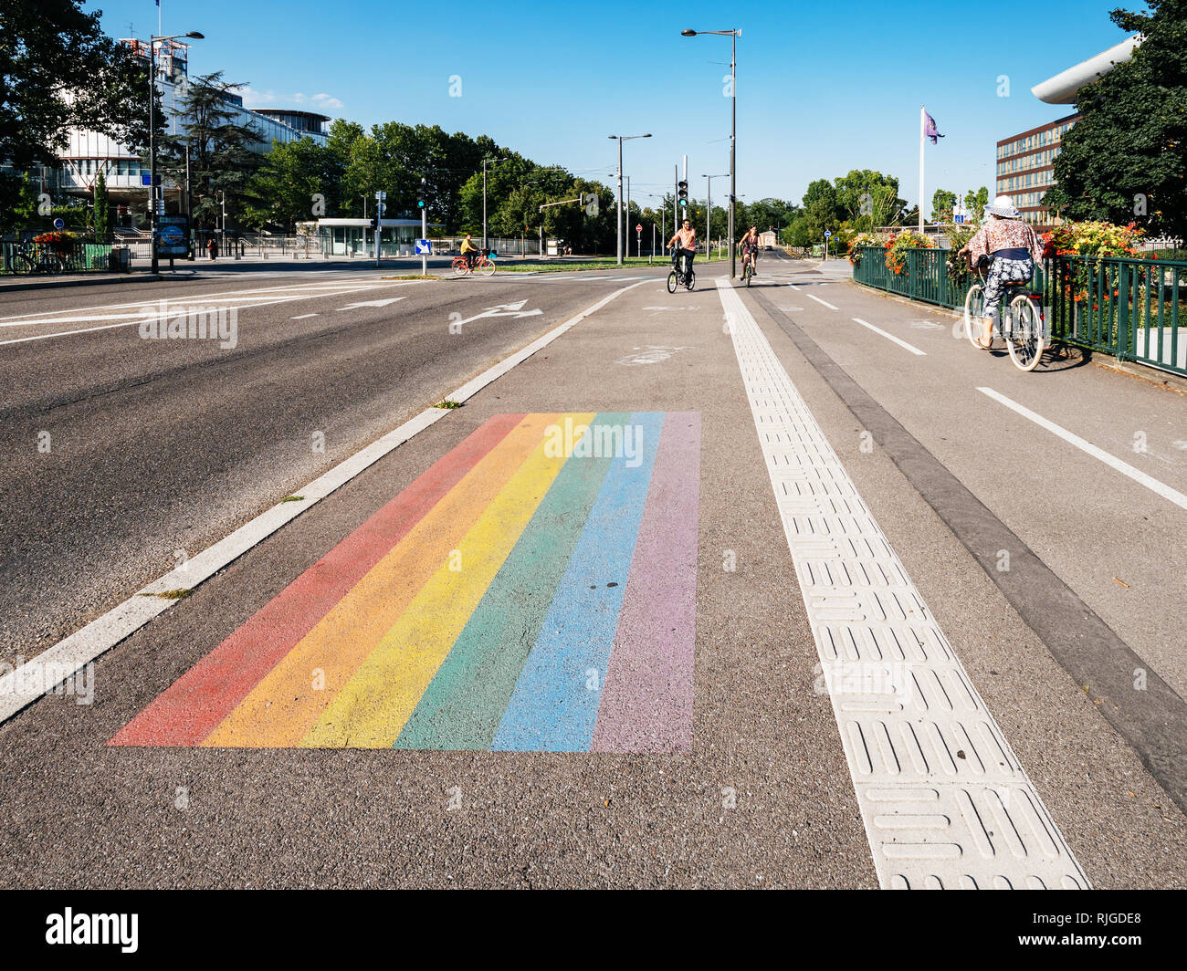 STRASBOURG, FRANCE - JUL 18, 2018: Gay pride LGBT flag in front of the European Court of Human Rights building with buses, cars and pedestrians in the evening Stock Photo