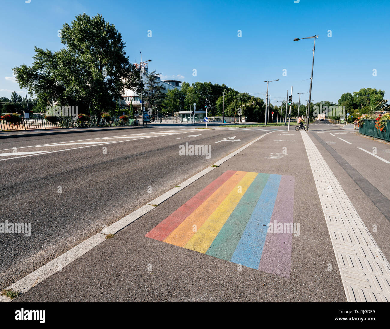 STRASBOURG, FRANCE - JUL 18, 2018: Empty street with gay pride LGBT flag in front of the European Court of Human Rights building with buses, cars and pedestrians in the evening Stock Photo